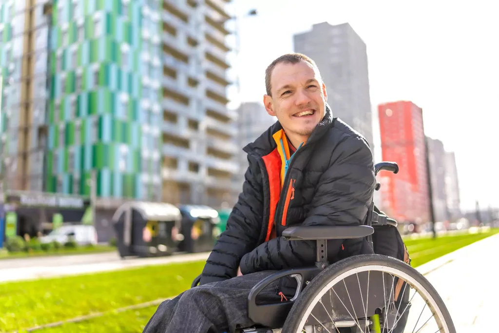 A disabled young man is smiling while spending time outdoors
