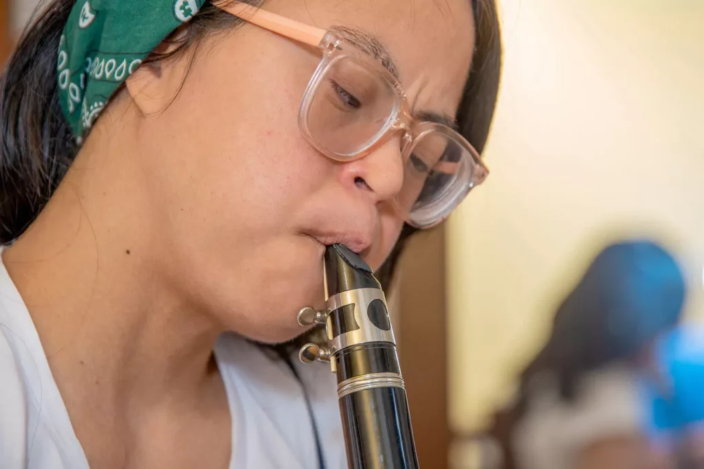A young woman with down syndrome is learning to play the flute